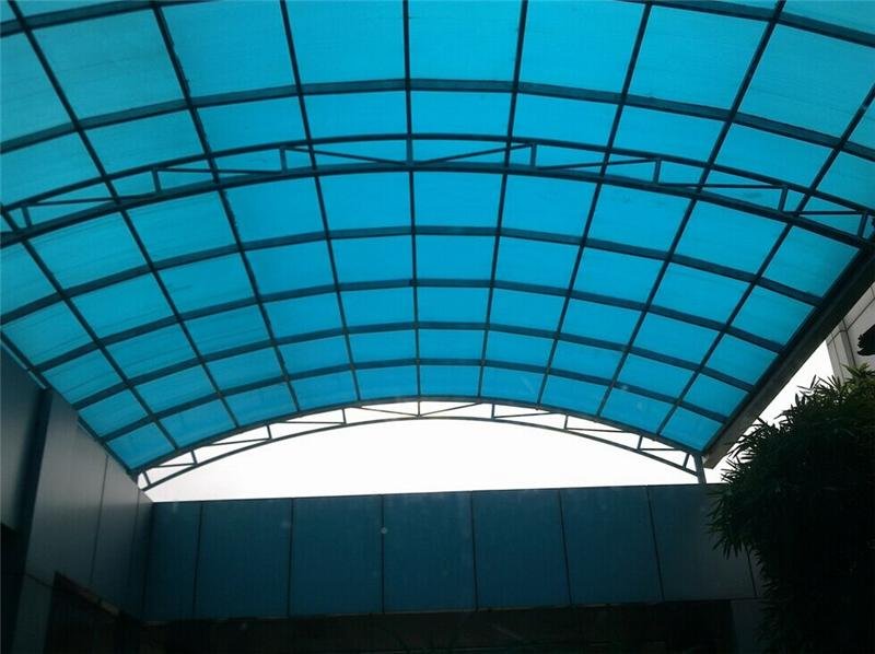 Arched polycarbonate canopy structure with blue translucent sheets showing a commercial building application