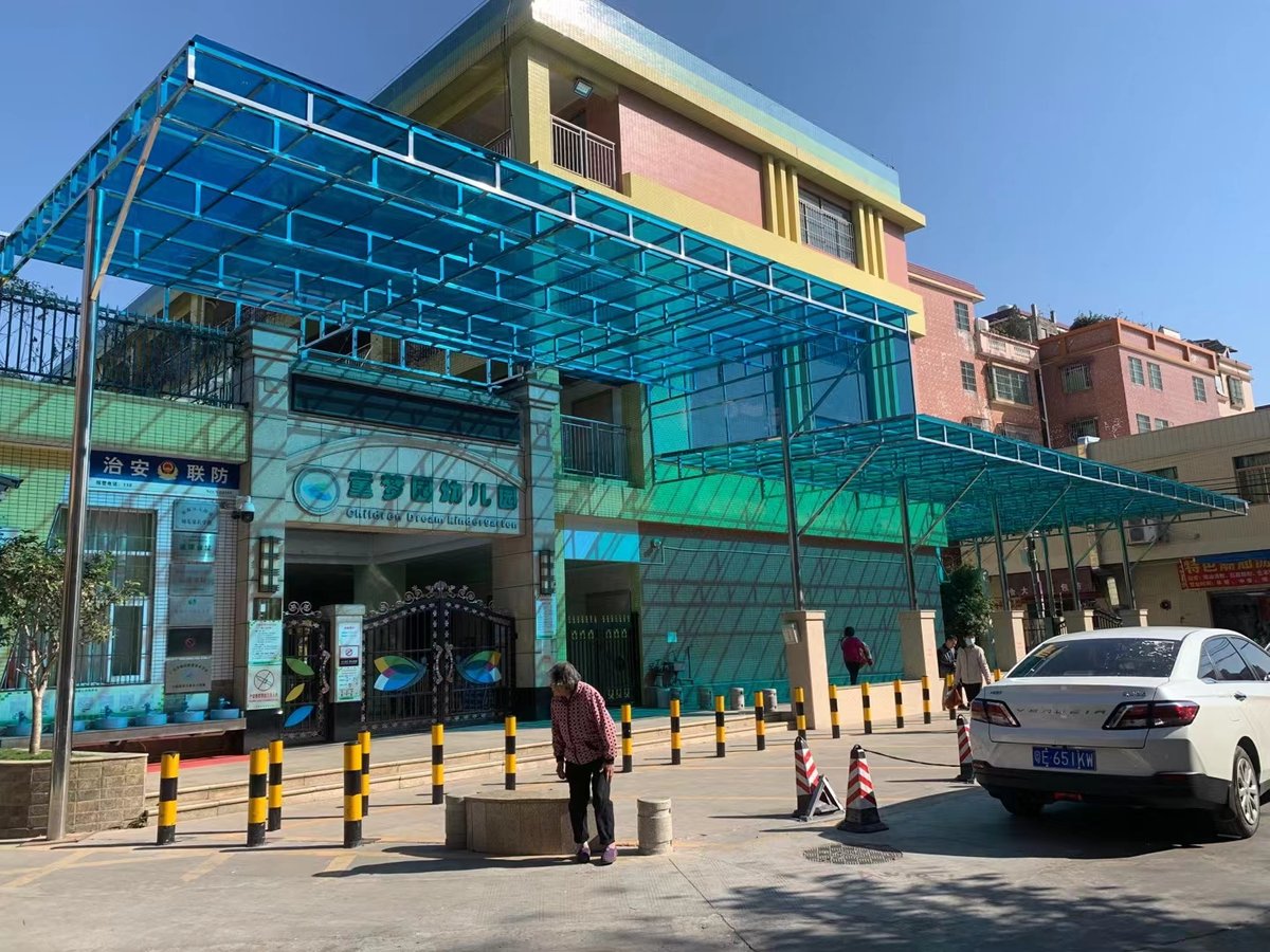 Blue solid polycarbonate sheet canopy installed at a kindergarten entrance, providing shade and weather protection with natural daylight transmission