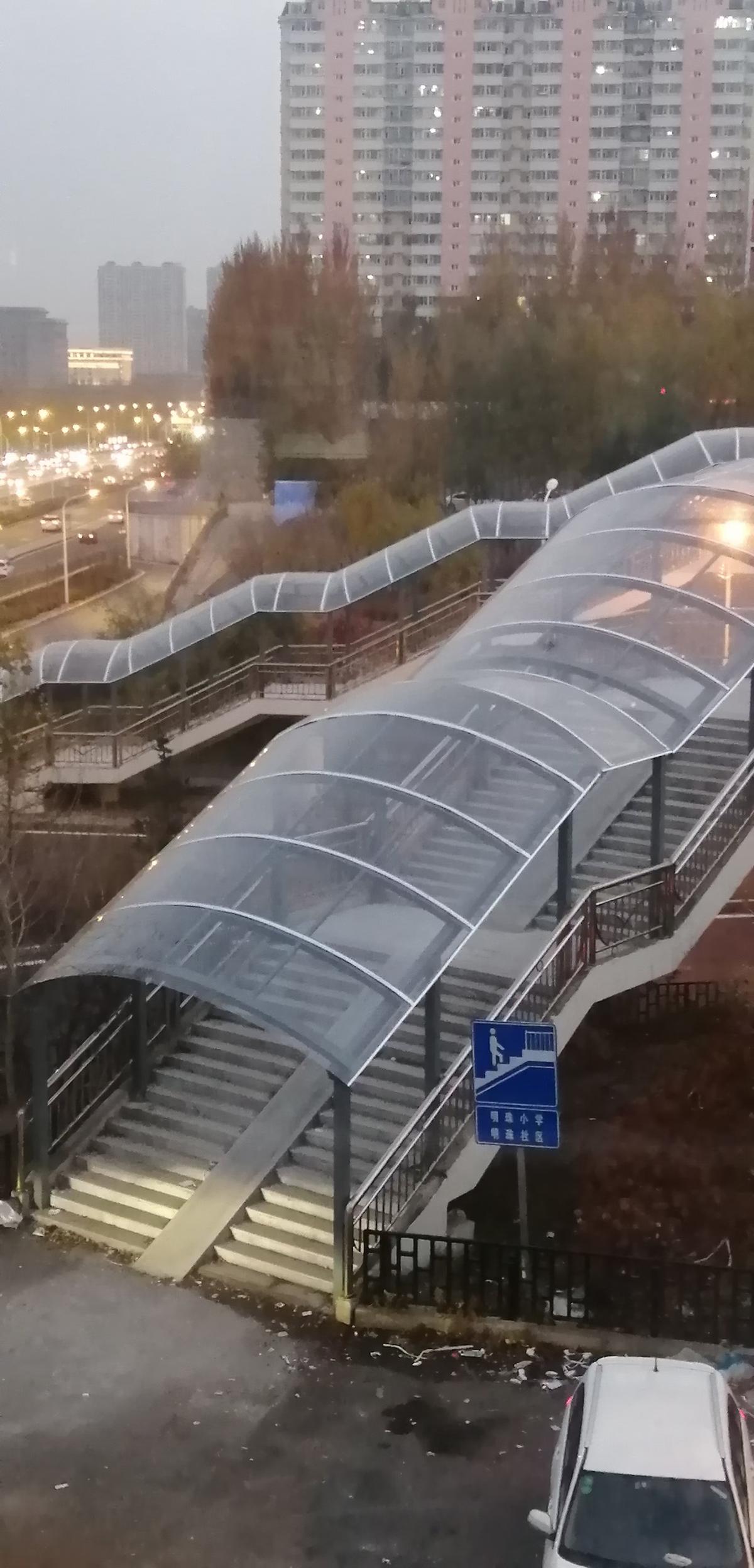 Pedestrian overpass with solid polycarbonate canopy in urban setting