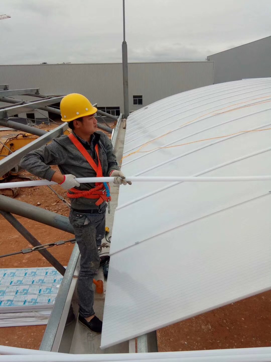 Worker installing U-Lock polycarbonate panels on an industrial factory roof, demonstrating the U-shaped lock connection and nail-free installation method