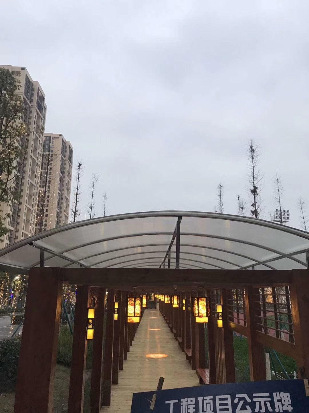Polycarbonate walkway canopy over a landscaped pedestrian route