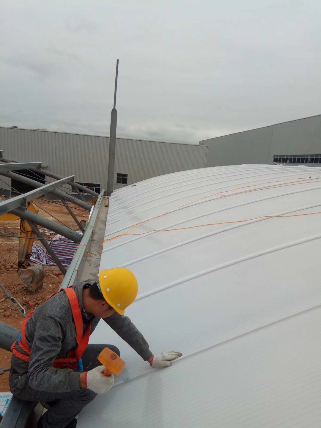 Workers installing arched U-Lock polycarbonate panels on a factory daylighting roof
