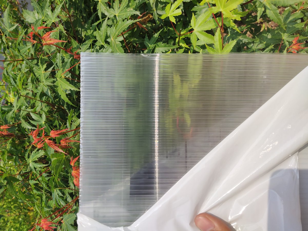 Clear polycarbonate sheet showing high transparency with protective film being peeled
