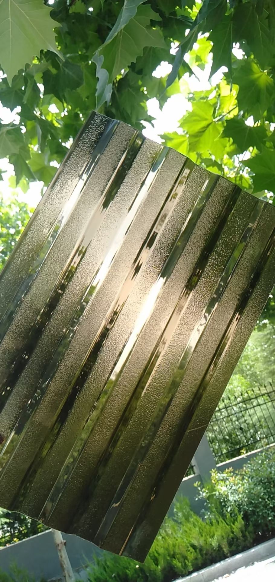 Light-diffusing polycarbonate sheet sample shown outdoors against green foliage