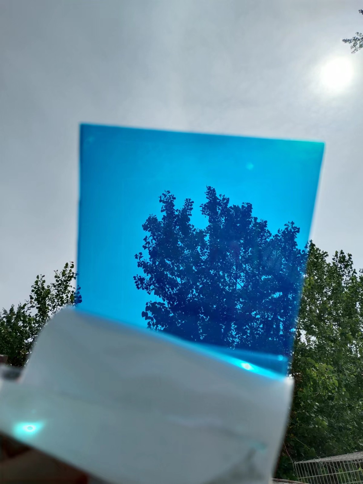 Blue solid polycarbonate sheet held up to the light showing its transparency