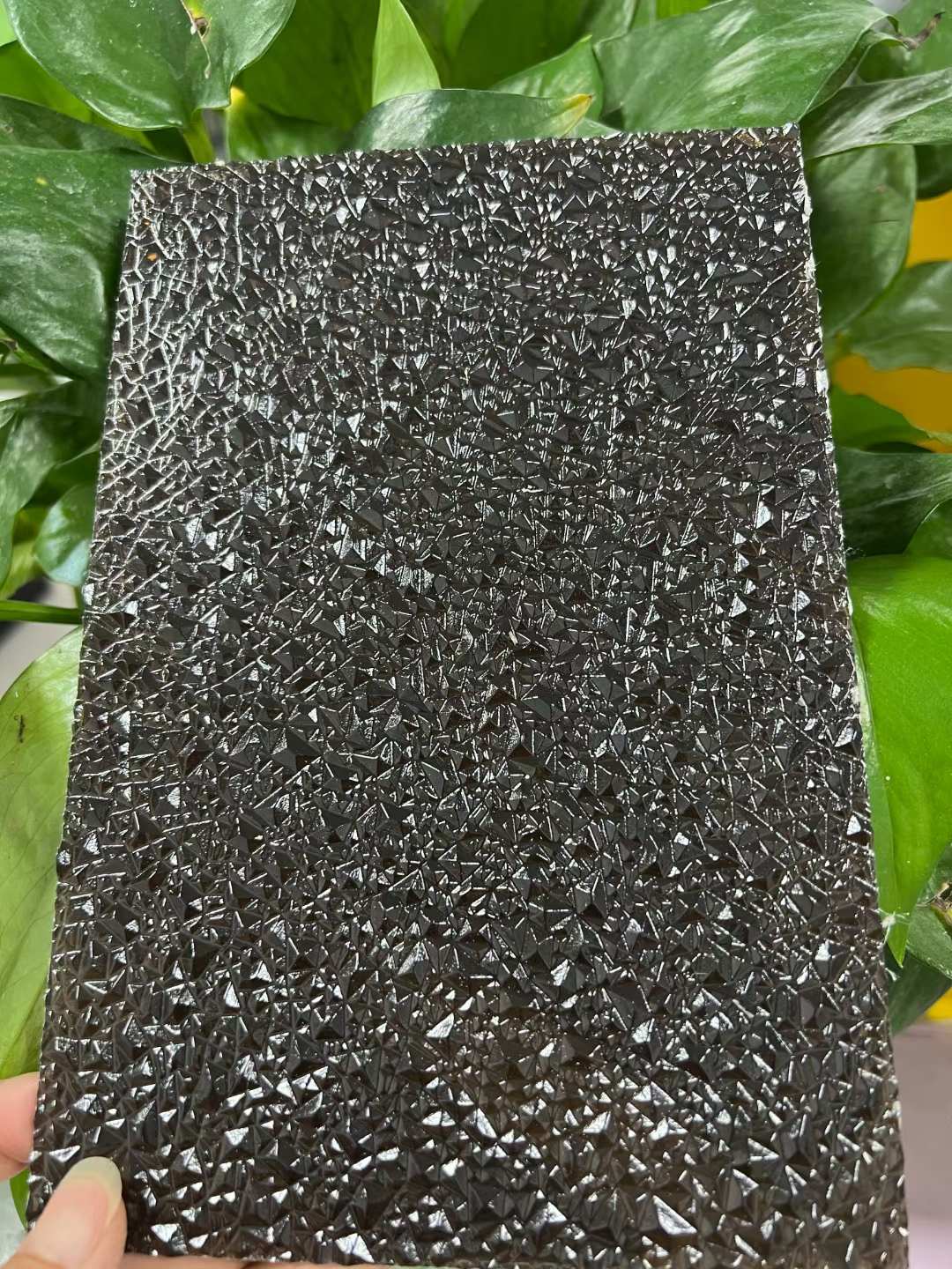 Close-up of the faceted diamond pattern on a black textured polycarbonate sheet