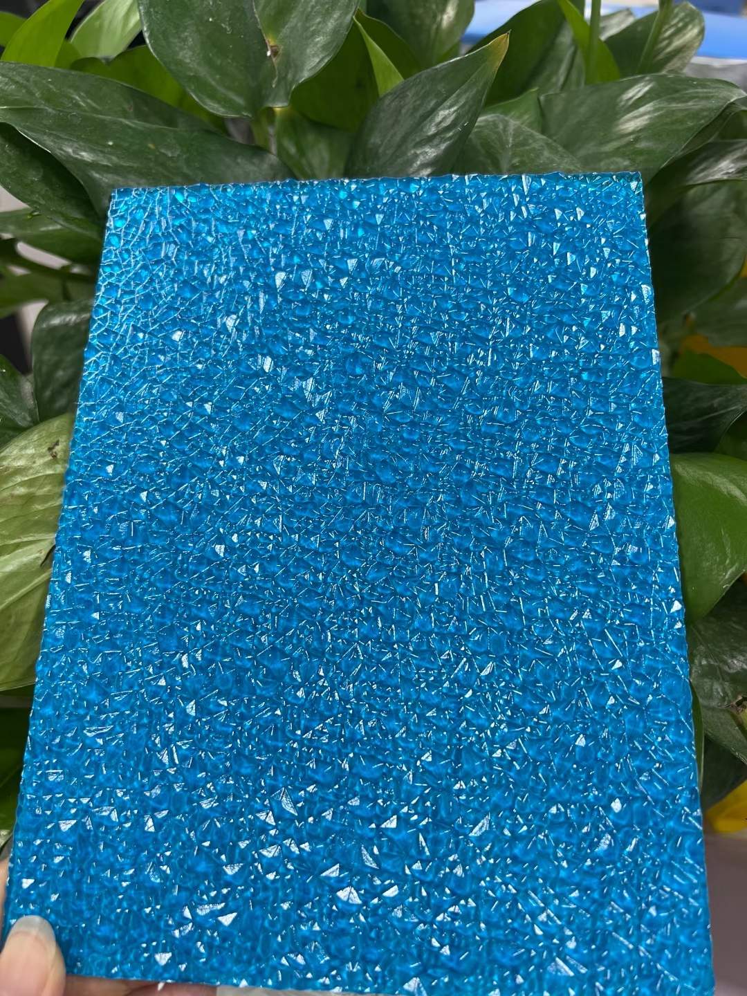 Blue textured polycarbonate sheet with diamond pattern held up against a green plant background