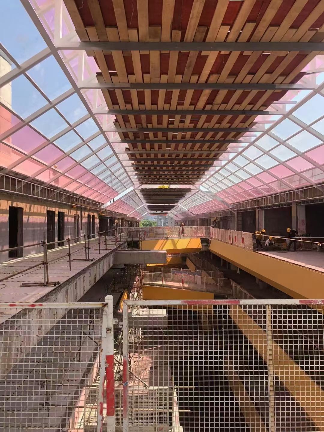 Solid polycarbonate canopy over a commercial atrium, transparent and pink-tinted panels