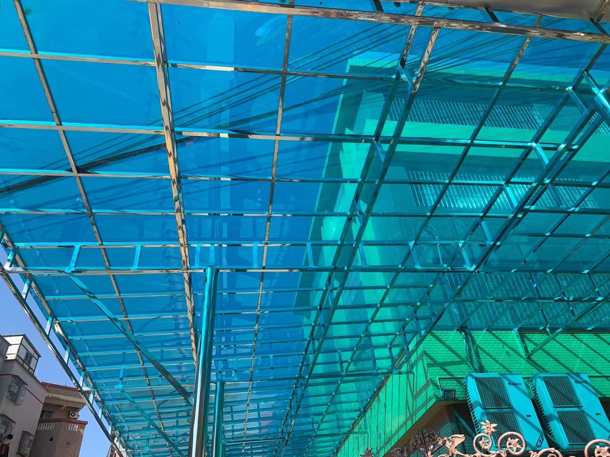 Blue polycarbonate walkway canopy over an open corridor